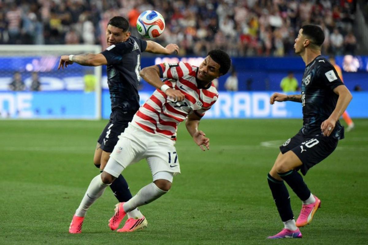 Paraguay's defender #04 Juan Jose Caceres (L) and US midfielder #17 Malik Tillman (C) fight for the ball during the 2026 World Cup Group D football match between USA and Paraguay at the Los Angeles Stadium in Inglewood on June 12, 2026.  Patrick T. Fallon / AFP