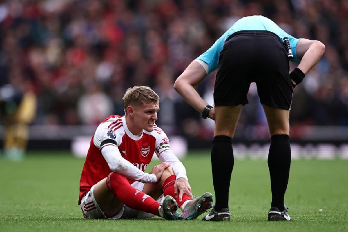 Arsenal's Norwegian midfielder #08 Martin Odegaard (L) reacts after picking up an injury during the English Premier League football match between Arsenal and West Ham United at the Emirates Stadium in London on October 4, 2025.   HENRY NICHOLLS / AFP