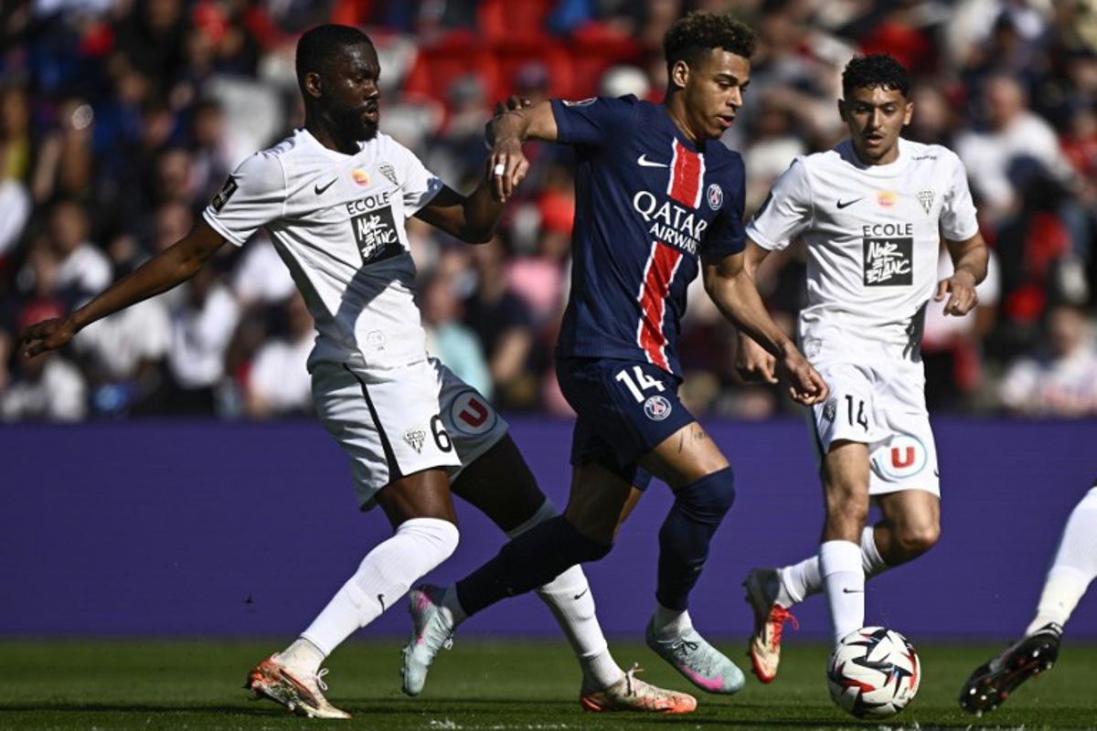 Paris Saint-Germain's French midfielder #14 Desire Doue fights for the ball with Angers' Ivorian midfielder #06 Jean-Eudes Aholou during the French L1 football match between Paris Saint-Germain (PSG) and SCO Angers at The Parc des Princes Stadium in Paris on April 5, 2025.  JULIEN DE ROSA / AFP