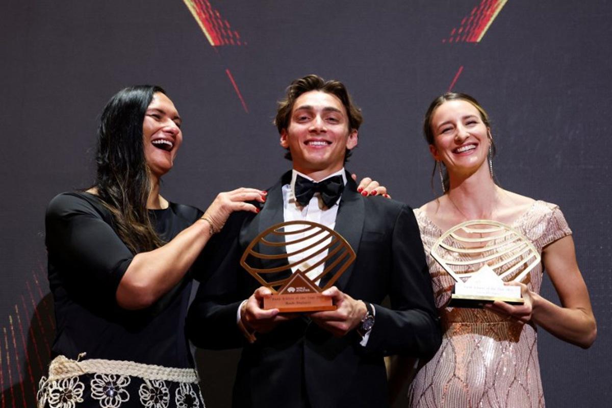 Sweden's world pole vault champion Armand Duplantis (C) holds his Men's field athlete of the year award and Australia's world high jump champion Nicola Olyslagers (R) holds her Women's field athlete of the year award as they pose on stage during the World Athletics Awards 2025 in Monaco, on November 30, 2025.  Valery HACHE / AFP