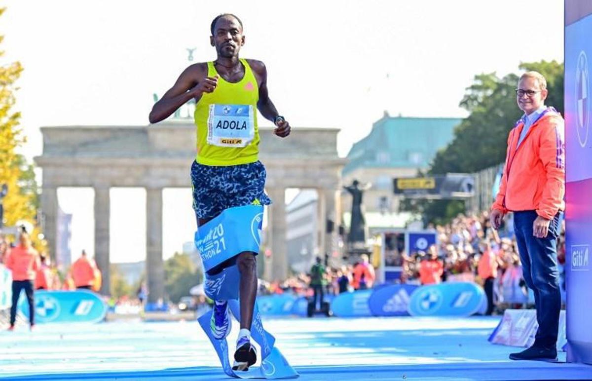 Ethiopia's GuyeAdola runs to win the Berlin Marathon on September 26, 2021 in front of Brandenburg Gate in Berlin, as Berlin's Mayor Michael Mueller (R) looks on.   Tobias SCHWARZ / AFP