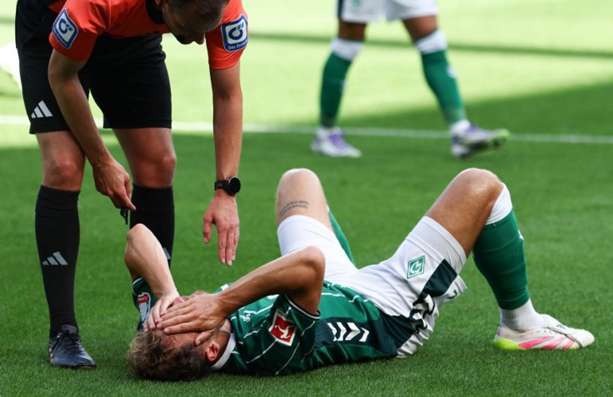 Bremen's Belgian midfielder #14 Senne Lynen lies on the pitch during the German first division Bundesliga football match between Werder Bremen and Bayer Leverkusen in Bremen on August 30, 2025.  Ibrahim OT / AFP