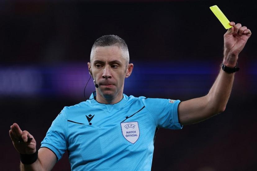 Romanian referee Radu Petrescu presents a yellow card during the UEFA Champions League, league phase football match between SL Benfica and Bologna FC 1909 at Estadio da Luz in Lisbon on December 11, 2024.   FILIPE AMORIM / AFP