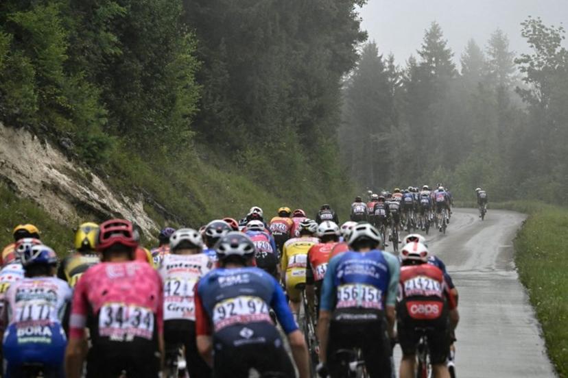 The pack of riders (peloton) cycles in the rain during the 20th stage of the 112th edition of the Tour de France cycling race, 184.2 km between Nantua and Pontarlier, in the Jura, eastern France, on July 26, 2025.  Loic VENANCE / AFP