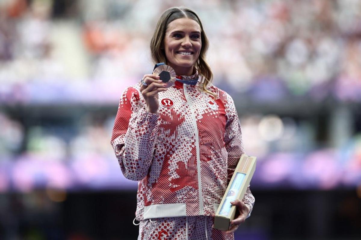 Bronze medallist Canada's Alysha Newman celebrates on the podium during the victory ceremony for the women's pole vault final athletics event at the Paris 2024 Olympic Games at Stade de France in Saint-Denis, north of Paris, on August 8, 2024.  Anne-Christine POUJOULAT / AFP