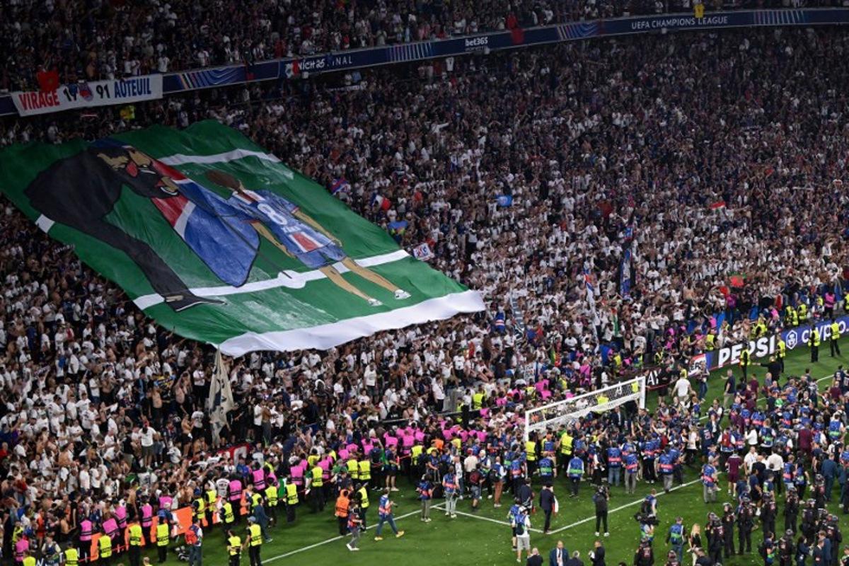 Paris Saint-Germain fans display a banner in the tribunes depicting Paris Saint-Germain's Spanish head coach Luis Enrique planting a flag for his late daughter Xana after the UEFA Champions League final football match between Paris Saint-Germain (PSG) and Inter Milan in Munich, southern Germany on May 31, 2025.  Kirill KUDRYAVTSEV / AFP