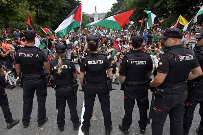 Basque regional police 'Ertzaintza' officers stand as pro-Palestinian protesters holding Palestinian flags demonstrate following the Vuelta 11th stage, in Bilbao, on September 3, 2025. Pro-Palestinian protest forces Vuelta stage to be shortened and to take the time at 3 kilometres before the line, according to the organisers, AFP reports. ANDER GILLENEA / AFP