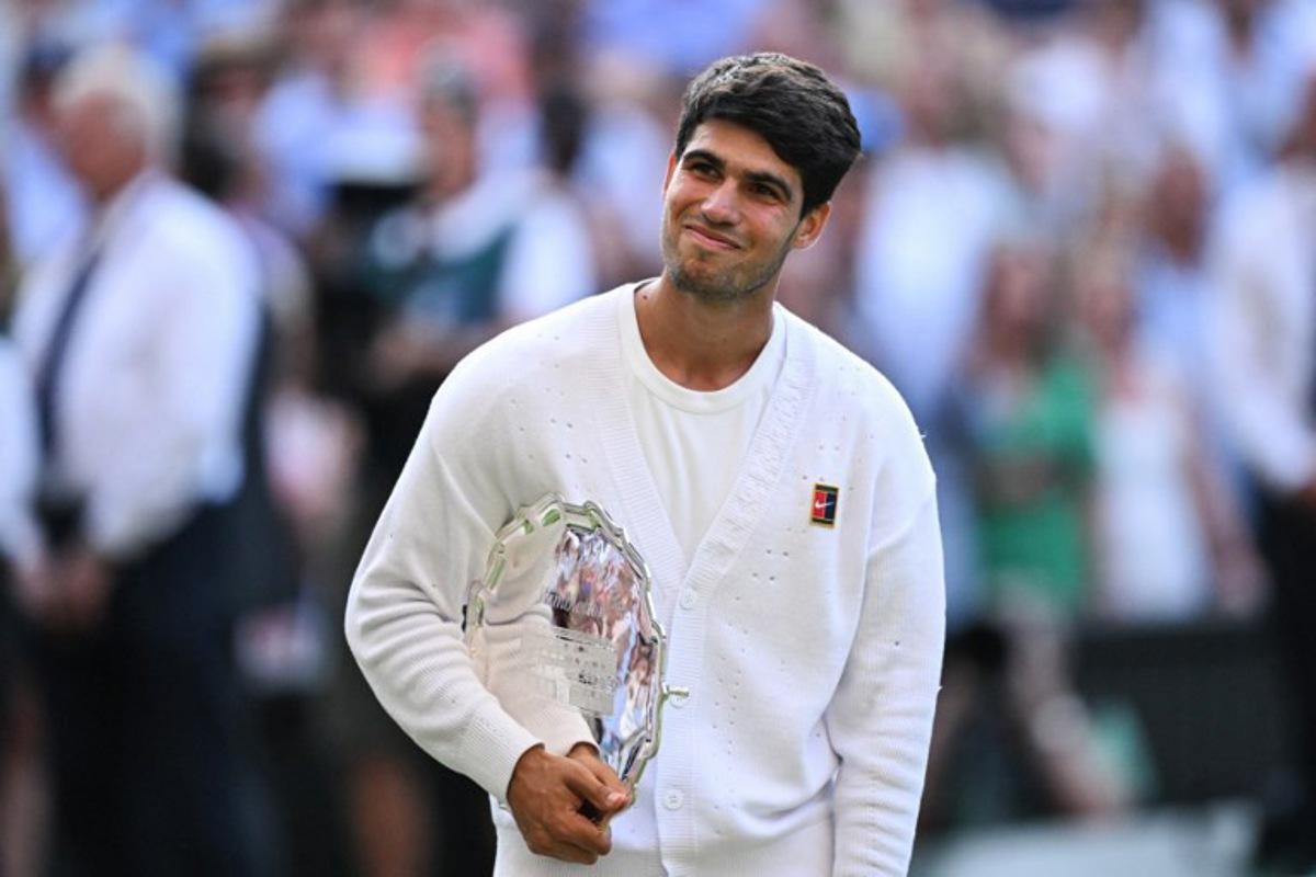 Spain's Carlos Alcaraz poses with the runner's up trophy, following his defeat against Italy's Jannik Sinner at the end of their men's singles final tennis match on the fourteenth day of the 2025 Wimbledon Championships at The All England Lawn Tennis and Croquet Club in Wimbledon, southwest London, on July 13, 2025.  Kirill KUDRYAVTSEV / AFP