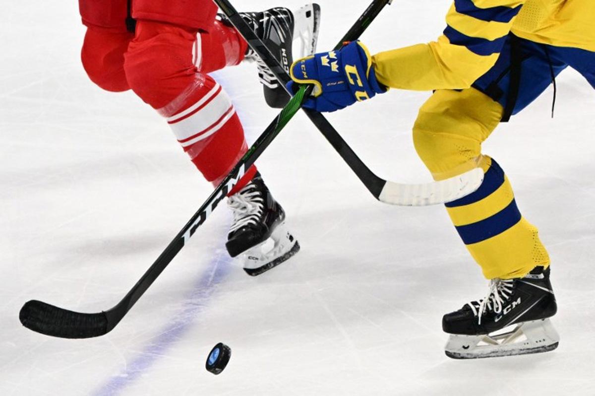 Sweden's Jessica Adolfsson vies for the puck with Denmark's Josefine Jakobsen during their women's preliminary round group B match of the Beijing 2022 Winter Olympic Games ice hockey competition, at the Wukesong Sports Centre in Beijing on February 8, 2022.  ANTHONY WALLACE / AFP