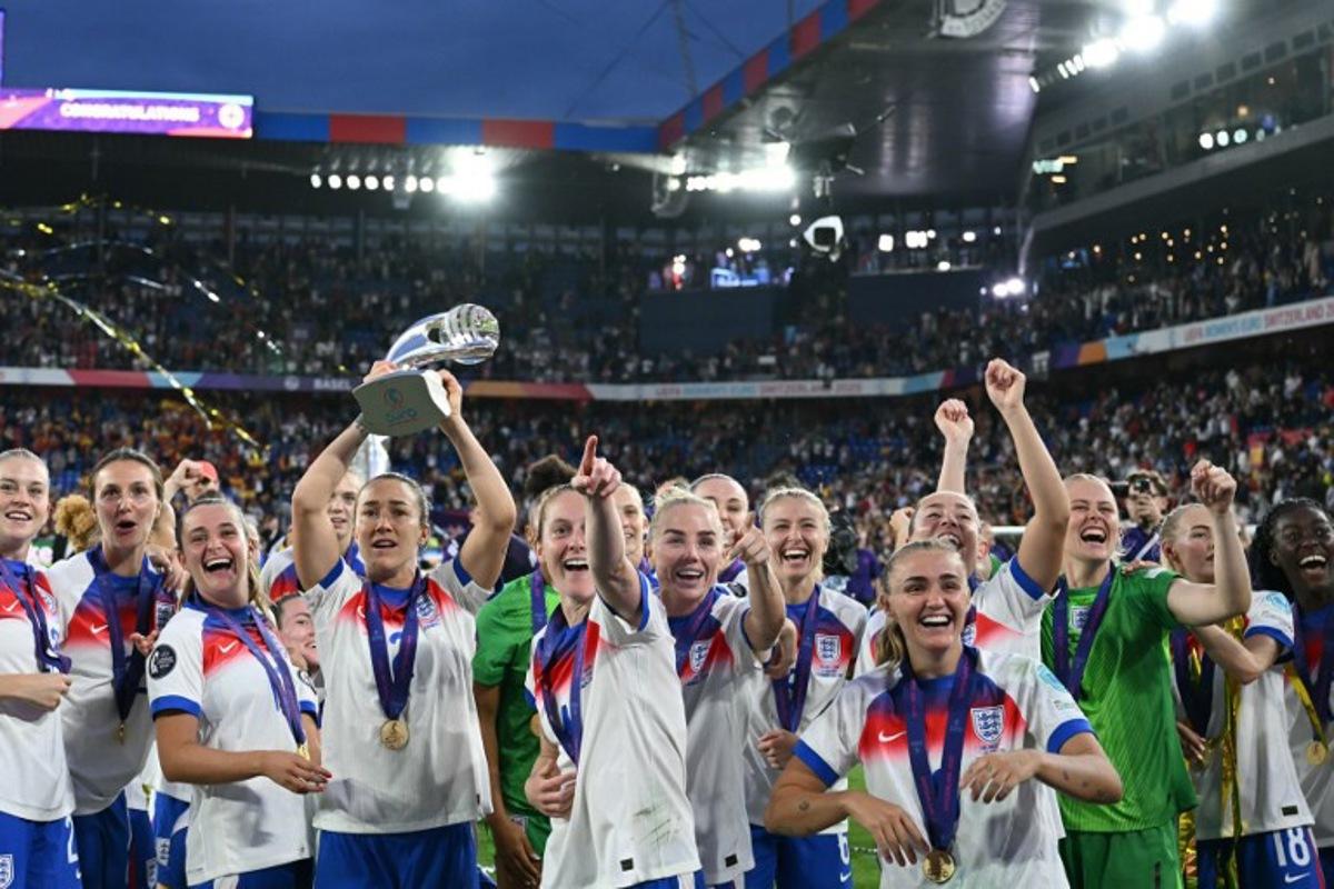 England players hold up the trophy to supporters as they celebrate England winning in the UEFA Women's Euro 2025 final football match between England and Spain at the St. Jakob-Park Stadium in Basel, on July 27, 2025. England beat Spain 3-1 on penalties to win the Women's Euro 2025. SEBASTIEN BOZON / AFP