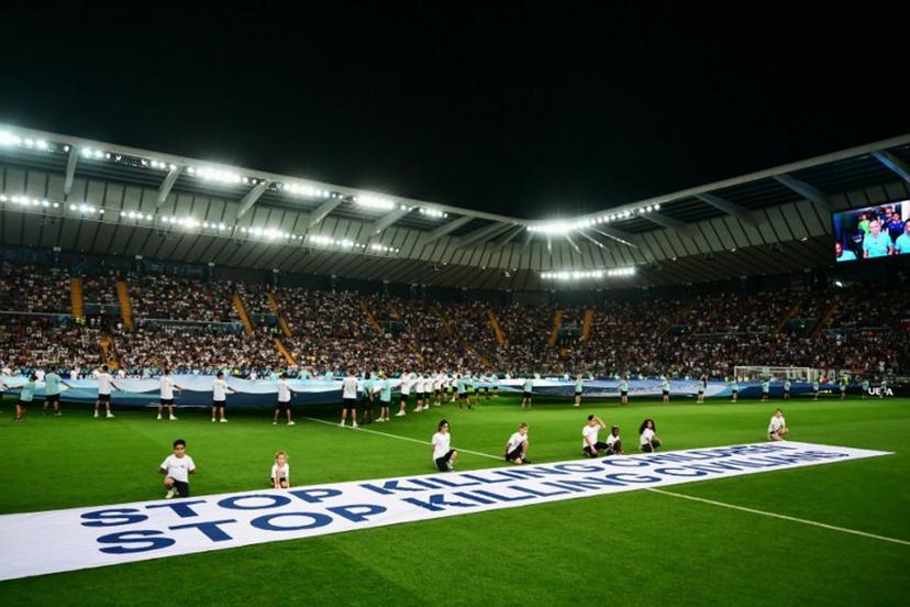 Mascots hold a banner which reads "Stop killing children, Stop killing civilians" on the pitch ahead of the 2025 UEFA Super Cup final football match between Paris Saint-Germain (FRA) and Tottenham Hotspur FC (ENG) at the Friuli stadium, in Udine, on August 13, 2025.  Marco BERTORELLO / AFP