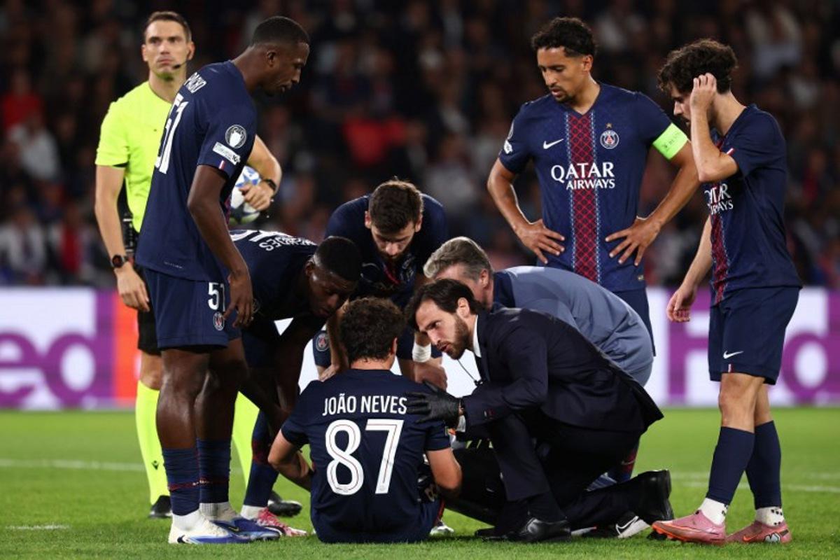 Paris Saint-Germain's Portuguese midfielder #87 Joao Neves (C) sits on the pitch as he receives medical attention during the UEFA Champions League first round day 1 football match between Paris Saint-Germain (FRA) and Atalanta (ITA) at the Parc des Princes stadium in Paris on September 17, 2025.  FRANCK FIFE / AFP