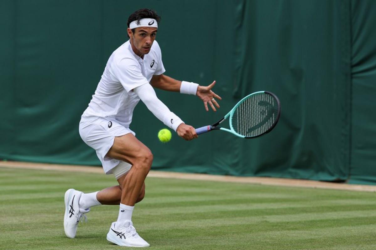 Italy's Lorenzo Musetti plays a backhand return to Georgia's Nikoloz Basilashvili during their men's singles first round tennis match on the second day of the 2025 Wimbledon Championships at The All England Lawn Tennis and Croquet Club in Wimbledon, southwest London, on July 1, 2025.  Adrian Dennis / AFP
