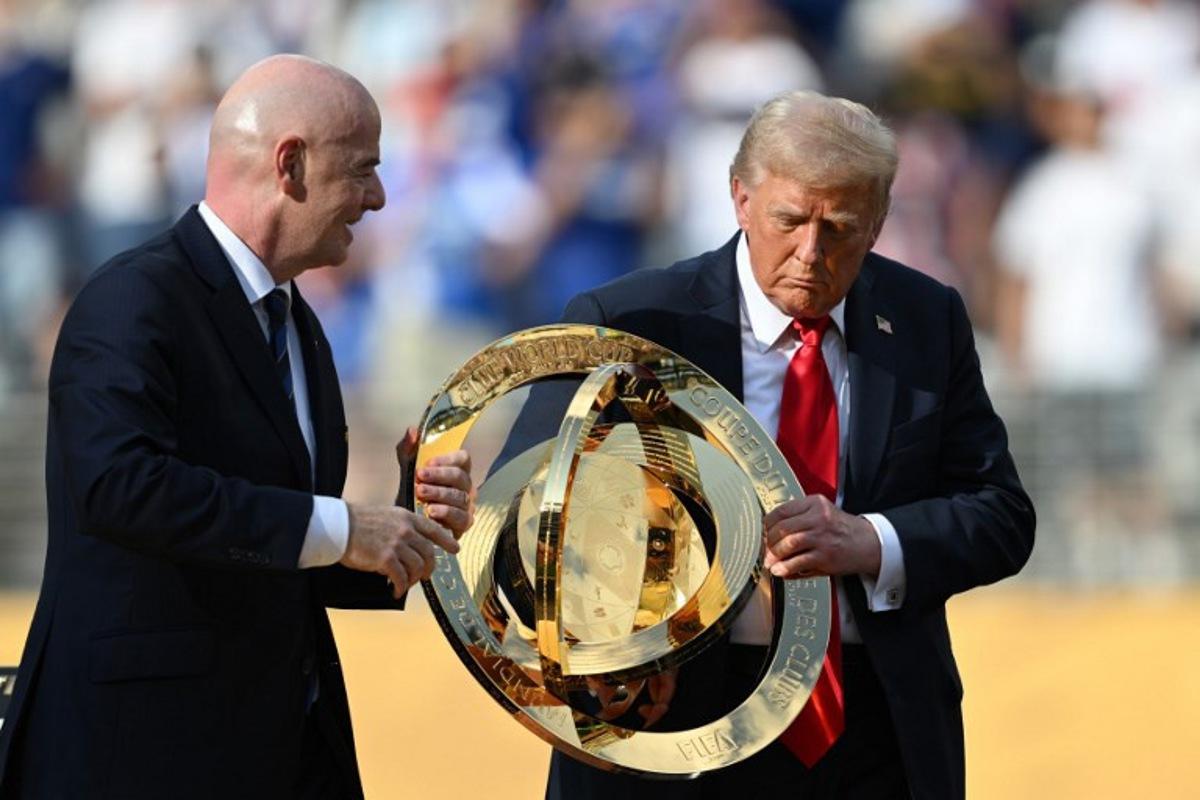 FIFA President Gianni Infantino (L) and US President Donald Trump carry the trophy during the award ceremony for the FIFA Club World Cup 2025 Champions, following the final football match between England's Chelsea and France's Paris Saint-Germain at the MetLife Stadium in East Rutherford, New Jersey on July 13, 2025.  ANGELA WEISS / AFP