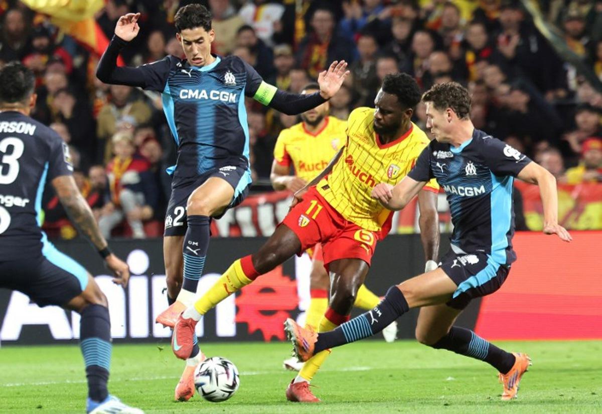 Lens' French forward #11 Odsonne Edouard (CR) fights for the ball with Marseille's Maroccan defender #21 Nayef Aguerd (CL) and Marseille's French defender #28 Benjamin Pavard (R) during the French L1 football match between RC Lens and Olympique de Marseille (OM) at the Stade Bollaert-Delelis in Lens, northern France, on October 25, 2025.  Francois LO PRESTI / AFP
