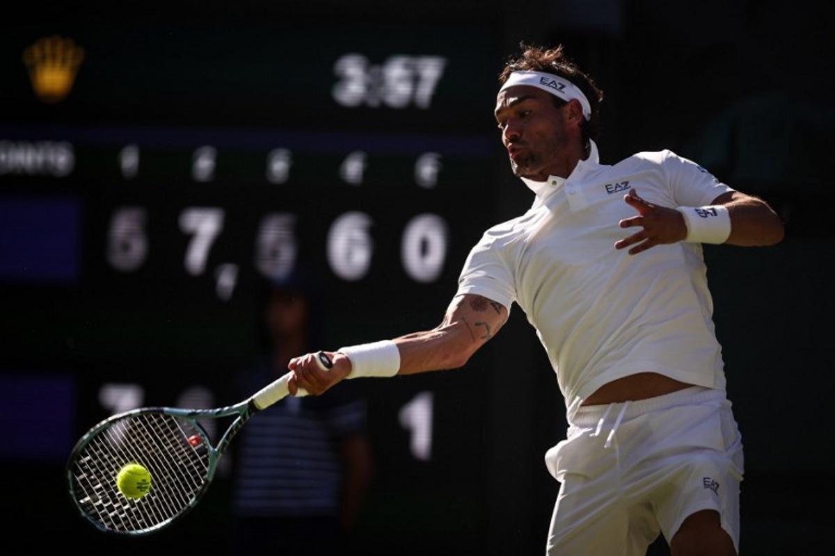 Italy's Fabio Fognini plays a forehand return to Spain's Carlos Alcaraz during their men's singles first round tennis match on the first day of the 2025 Wimbledon Championships at The All England Lawn Tennis and Croquet Club in Wimbledon, southwest London, on June 30, 2025.  HENRY NICHOLLS / AFP