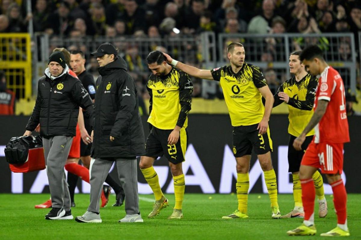 Dortmund's German midfielder #23 Emre Can (C) is consoled by his teammates including Dortmund's German defender #03 Waldemar Anton as he goes off after sustaining an injury during the German first division Bundesliga football match between BVB Borussia Dortmund and FC Bayern Munich in Dortmund, western Germany, on February 28, 2026.  INA FASSBENDER / AFP