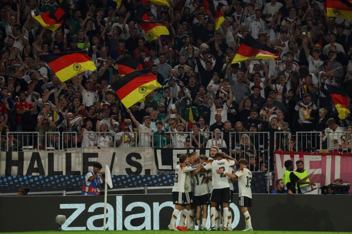 Germany's midfielder #08 Tom Bischof (hidden) celebrates scoring the opening goal with his teammates during the UEFA Nations League Group A2 between Germany and Serbia at the Allianz Arena in Munich, southern Germany on October 1, 2026.  Karl-Josef HILDENBRAND / AFP