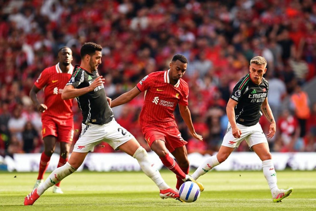 Liverpool's Dutch midfielder #38 Ryan Gravenberch (C) vies with Arsenal's Spanish midfielder #23 Mikel Merino (L) and Arsenal's Belgian midfielder #19 Leandro Trossard (R) during the English Premier League football match between Liverpool and Arsenal at Anfield in Liverpool, north west England on May 11, 2025. PETER POWELL / AFP