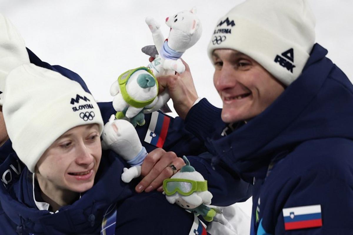 Slovenia's Nika Prevc (L) and Slovenia's Domen Prevc celebrate on the podium for the ski jumping mixed team final of the Milano Cortina 2026 Winter Olympic Games at Predazzo Ski Jumping Stadium in Predazzo (Val di Fiemme), on February 10, 2026. Anne-Christine POUJOULAT / AFP