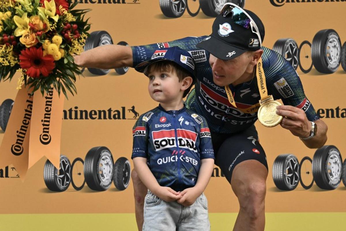 Soudal Quick-Step team's Belgian rider Tim Merlier celebrates on the podium with his son Jules after winning the 12th stage of the 113th edition of the Tour de France cycling race, 179,1 km between Circuit de Nevers Magny-Cours and Chalon-sur-Saône in central France, on July 16, 2026. Jeff PACHOUD / AFP