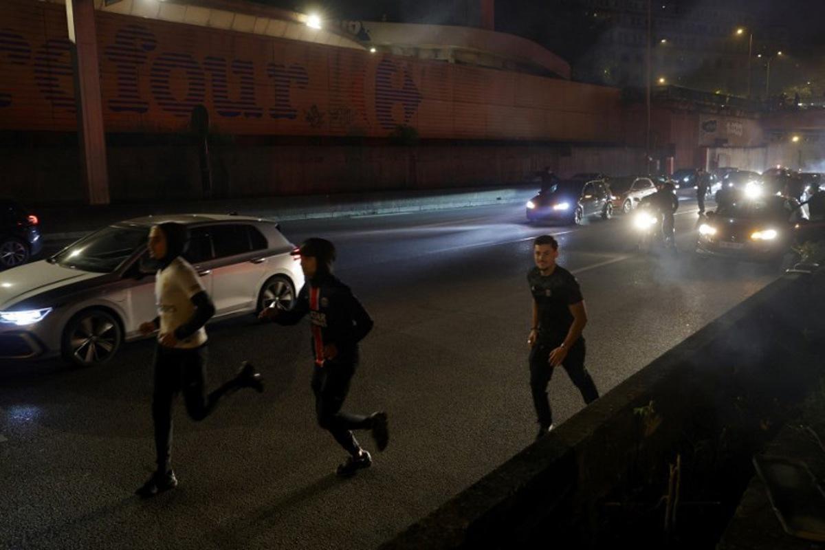 Paris Saint-Germain (PSG) supporters run after police used tear gas to disperse them after a group of supporters blocked the highway near the Parc des Princes Stadium in Paris on May 7, 2025, while they celebrated their team's victory in the UEFA Champions League semi-final second leg football match against Arsenal. GEOFFROY VAN DER HASSELT / AFP