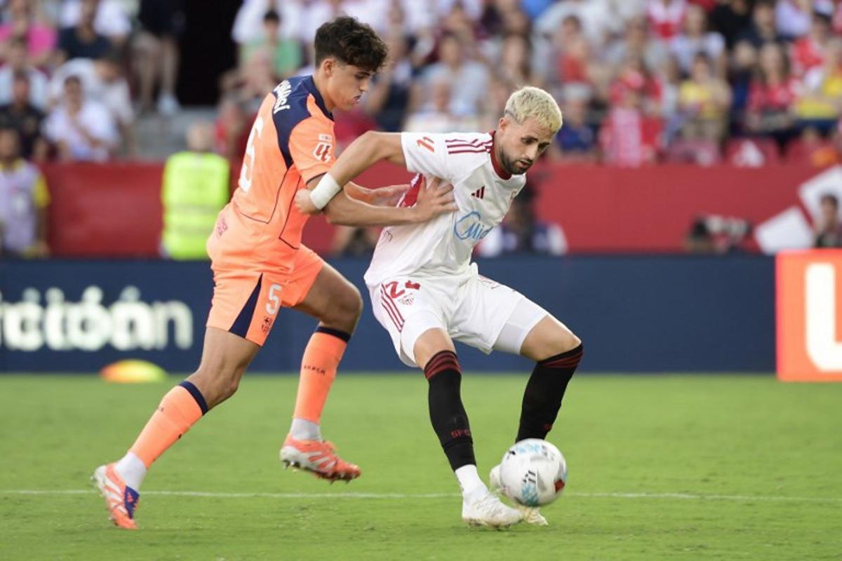 Barcelona's Spanish defender #05 Pau Cubarsi (L) and Sevilla's Belgian forward #24 Adnan Januzaj fight for the ball during the Spanish league football match between Sevilla FC and FC Barcelona at Ramon Sanchez Pizjuan Stadium in Seville on October 5, 2025. CRISTINA QUICLER / AFP