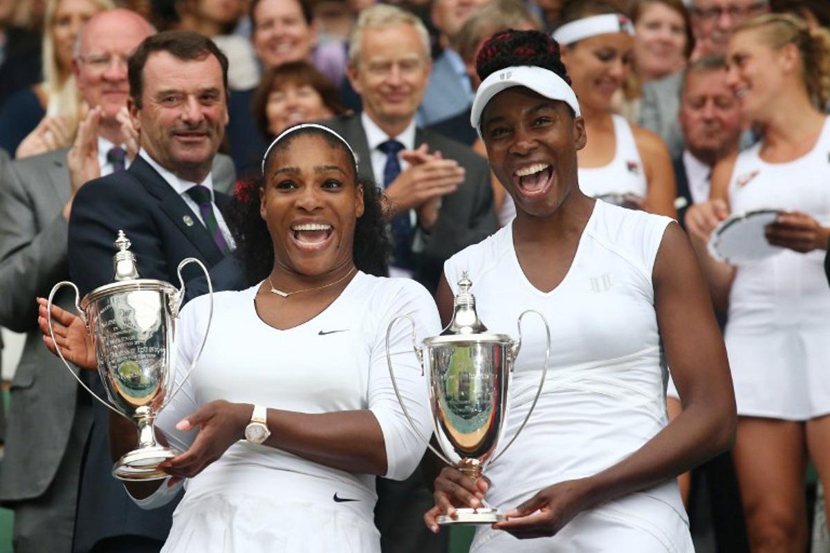 US player Serena Williams (L) and her partner US player Venus Williams (R) pose with the winner's trophies after beating Hungary's Timea Babos and Kazakhstan's Yaroslava Shvedova to win the women's doubles final on the thirteenth day of the 2016 Wimbledon Championships at The All England Lawn Tennis Club in Wimbledon, southwest London, on July 9, 2016. JUSTIN TALLIS / AFP