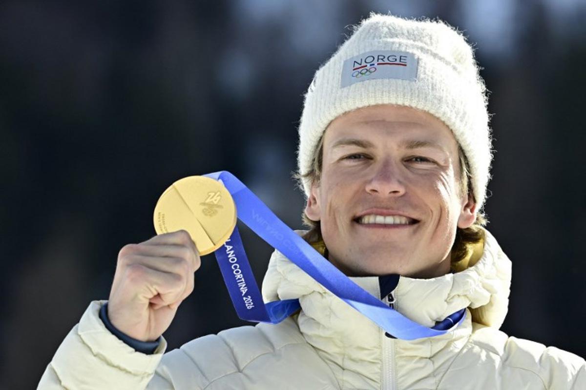 Gold medallist Norway's Johannes Hoesflot Klaebo celebrates on the podium for the men's cross country 10km + 10km skiathlon event of the Milano Cortina 2026 Winter Olympics at Tesero Cross-Country Skiing Stadium in Lago di Tesero (Val di Fiemme), on February 8, 2026. Tobias SCHWARZ / AFP