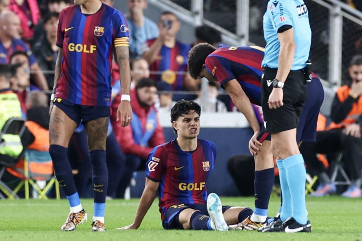 Barcelona's Spanish defender #12 Xavi Espart sits on the pitch after sustaining an injury during the Spanish league football match between FC Barcelona and Real Madrid CF at Camp Nou Stadium in Barcelona on October 25, 2026. Josep LAGO / AFP