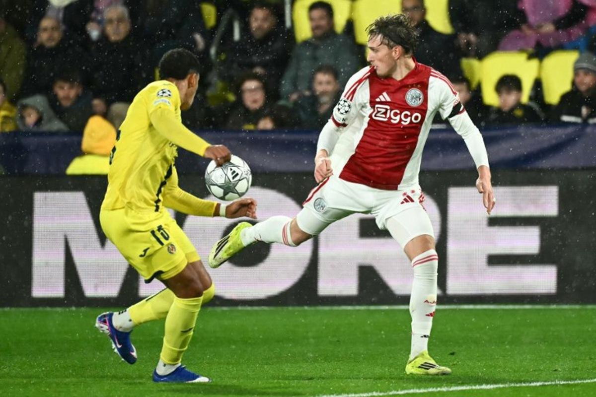 Ajax's Belgian forward #11 Mika Godts (R) controls the ball past Villarreal's Uruguayan defender #15 Santiago Mourino (L) during the UEFA Champions League league phase day 7 football match between Villarreal CF and Ajax at La Ceramica Stadium in Vila-real on January 20, 2026. JOSE JORDAN / AFP