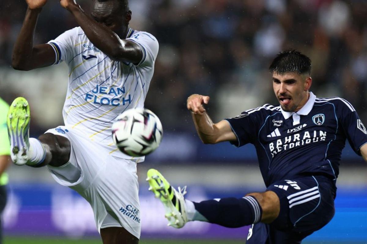 Paris FC's Belgian defender #28 Thibault De Smet (R) shoots the ball past Lorient's Ivorian forward #09 Mohamed Bamba during the French L1 football match between Paris FC and FC Lorient at the Stade Jean-Bouin in Paris on October 3, 2025. FRANCK FIFE / AFP