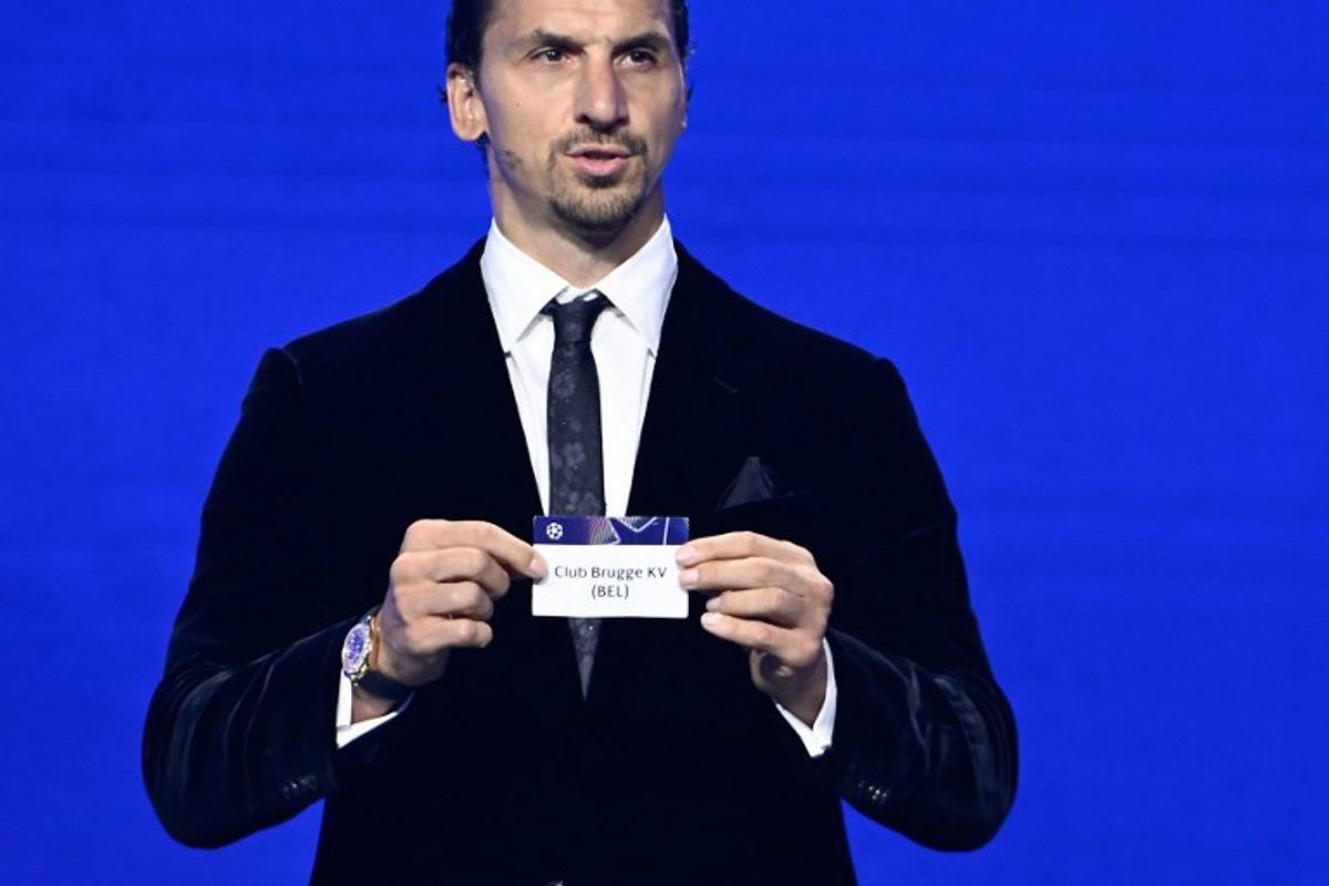AC Milan's Swedish senior advisor Zlatan Ibrahimovic holds up the slip of Club Brugge during the draw ceremony for the group stage of the 2025-2026 UEFA Champions League football tournament, at the Grimaldi Forum in Monaco on August 28, 2025. Frederic DIDES / AFP
