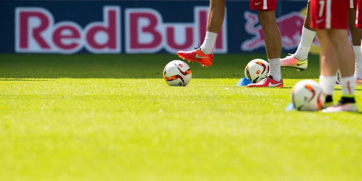 Football players warm up in front of a "Red Bull" advertising banner on display at the stadium prior to the German second division Bundesliga football match between RB Leipzig and Karlsruher SC at the Red Bull Arena in Leipzig, eastern Germany, on May 8, 2016. Leipzig won the match 2-0 and will be promoted to the first division Bundesliga next season. Robert MICHAEL / AFP
