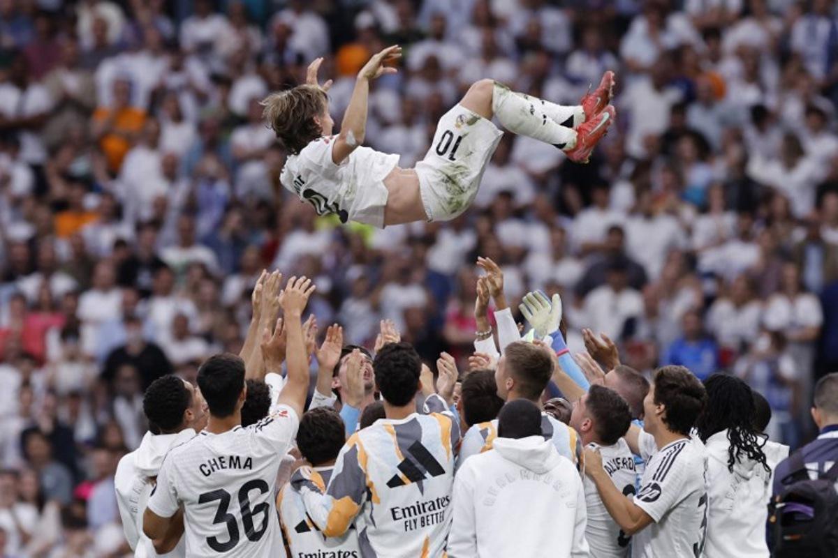 Real Madrid's Croatian midfielder #10 Luka Modric is tossed into the air by teammates at the end of the Spanish league football match between Real Madrid CF and Real Sociedad at Santiago Bernabeu Stadium in Madrid on May 24, 2025. OSCAR DEL POZO / AFP