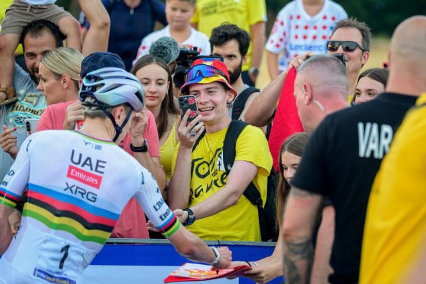 Tour de France's five-time winner Slovenian rider Tadej Pogacar (L) signs autographs as supporters take photograph ahead of the start of the Tadej Pogacar's Criterium Elite Men's race in his hometown in Komenda, Slovenia on July 31, 2026. Jure Makovec / AFP