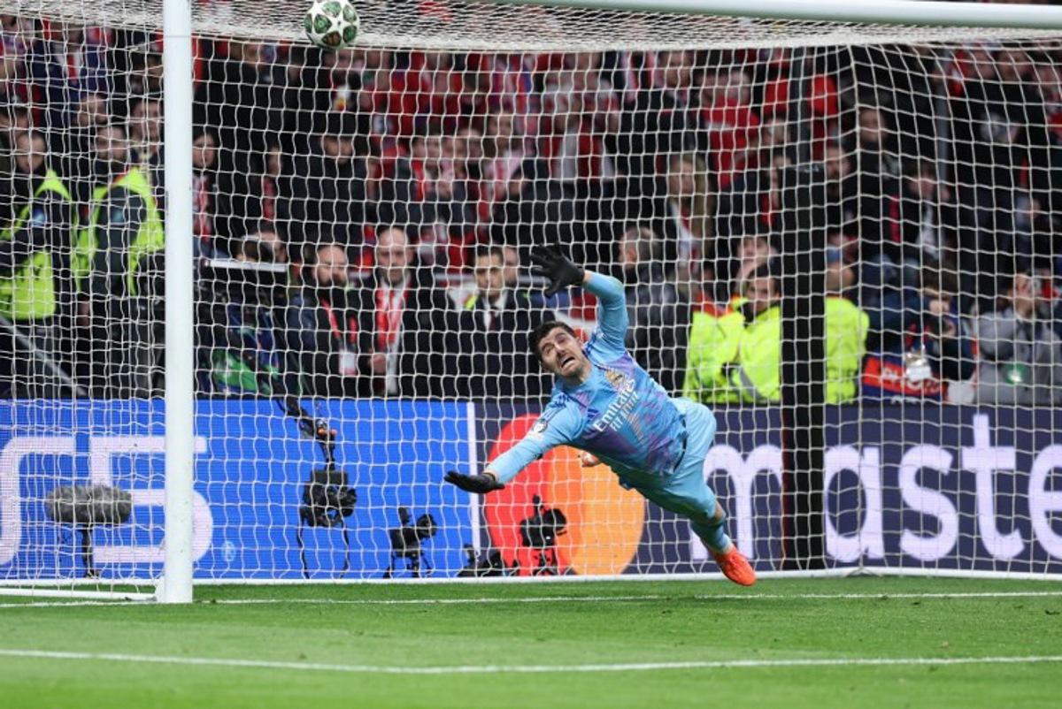 Real Madrid's Belgian goalkeeper #01 Thibaut Courtois dives for the ball during the penalty shoot out after the UEFA Champions League Round of 16 second leg football match between Club Atletico de Madrid and Real Madrid CF at the Metropolitano stadium in Madrid on March 12, 2025. Thomas COEX / AFP