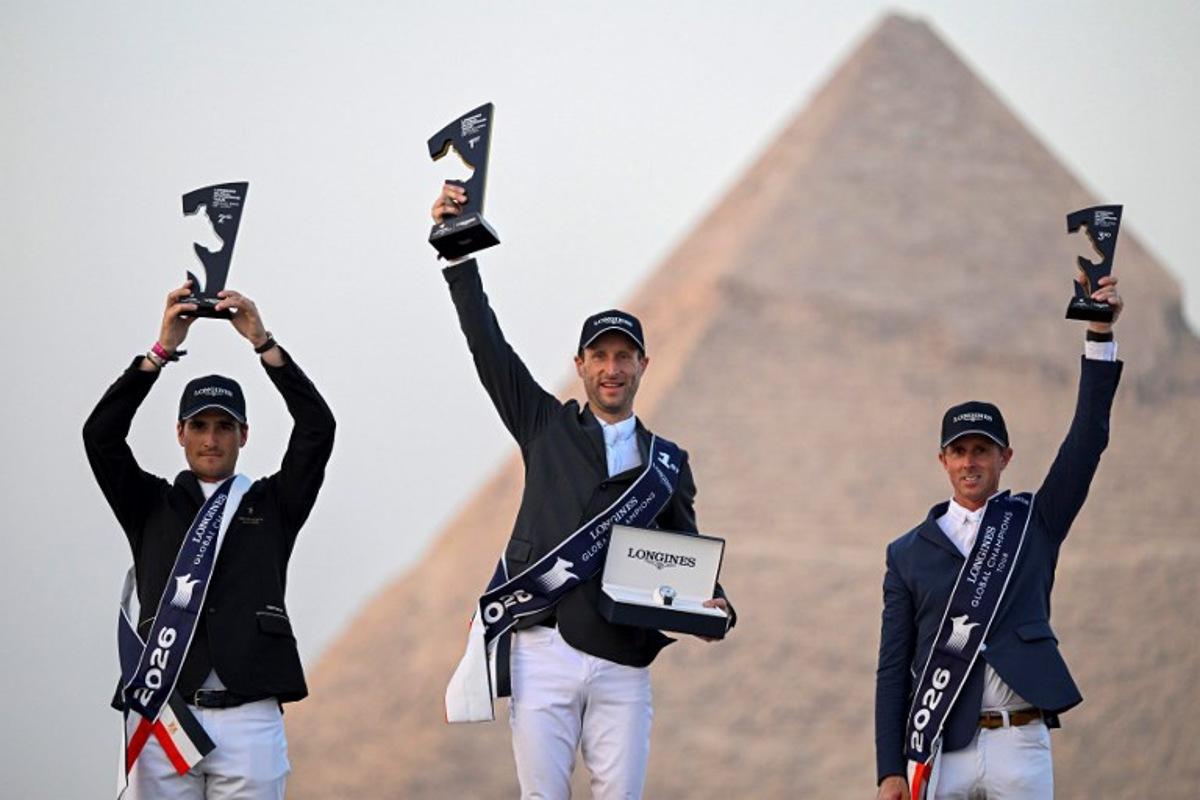 Belgium's first-place winner Pieter Devos (C), second-place winner Olivier Philippaerts (L), and England's third-place winner Ben Maher celebrate on the podium after the Longines Global Champions Tour 2026 at the Giza pyramids, west of Cairo on October 24, 2026. Khaled DESOUKI / AFP