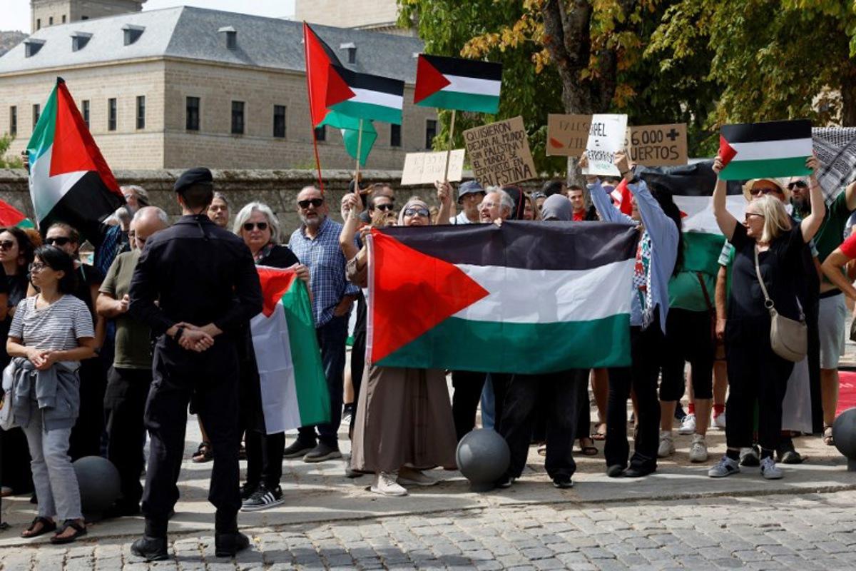 Guardia Civil officers stand as Pro-Palestinians protesters hold Palestinian flags and banners during the 20th stage of the Vuelta a Espana 2025, a 156 km race between Robledo de Chavela and Bola del Mundo, in El Escorial, on September 13, 2025. Pierre-Philippe MARCOU / AFP