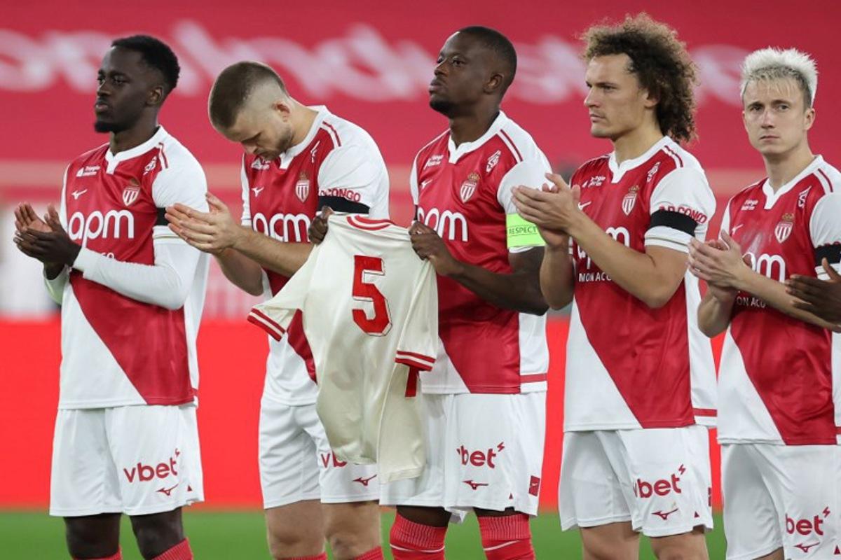 Monaco's Swiss midfielder #06 Denis Zakaria (C) holds a jersey of late Monaco player Rolland Coubis during a tribute before the French L1 football match between AS Monaco and FC Lorient at the Louis II Stadium (Stade Louis II) in the Principality of Monaco on January 16, 2026. Valery HACHE / AFP