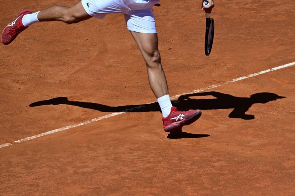 Serbia's Novak Djokovic casts a shadow on the clay court as he serves to Chile's Alejandro Tabilo during the Men's ATP Rome Open tennis tournament at Foro Italico in Rome on May 12, 2024. Tiziana FABI / AFP