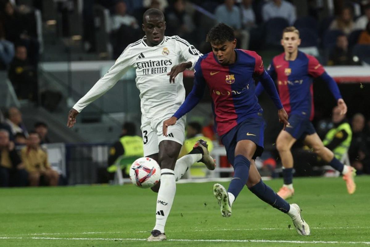 Barcelona's Spanish forward #19 Lamine Yamal (R) is challenged by Real Madrid's French defender #23 Ferland Mendy during the Spanish league football match between Real Madrid CF and FC Barcelona at the Santiago Bernabeu stadium in Madrid on October 26, 2024. Pierre-Philippe MARCOU / AFP