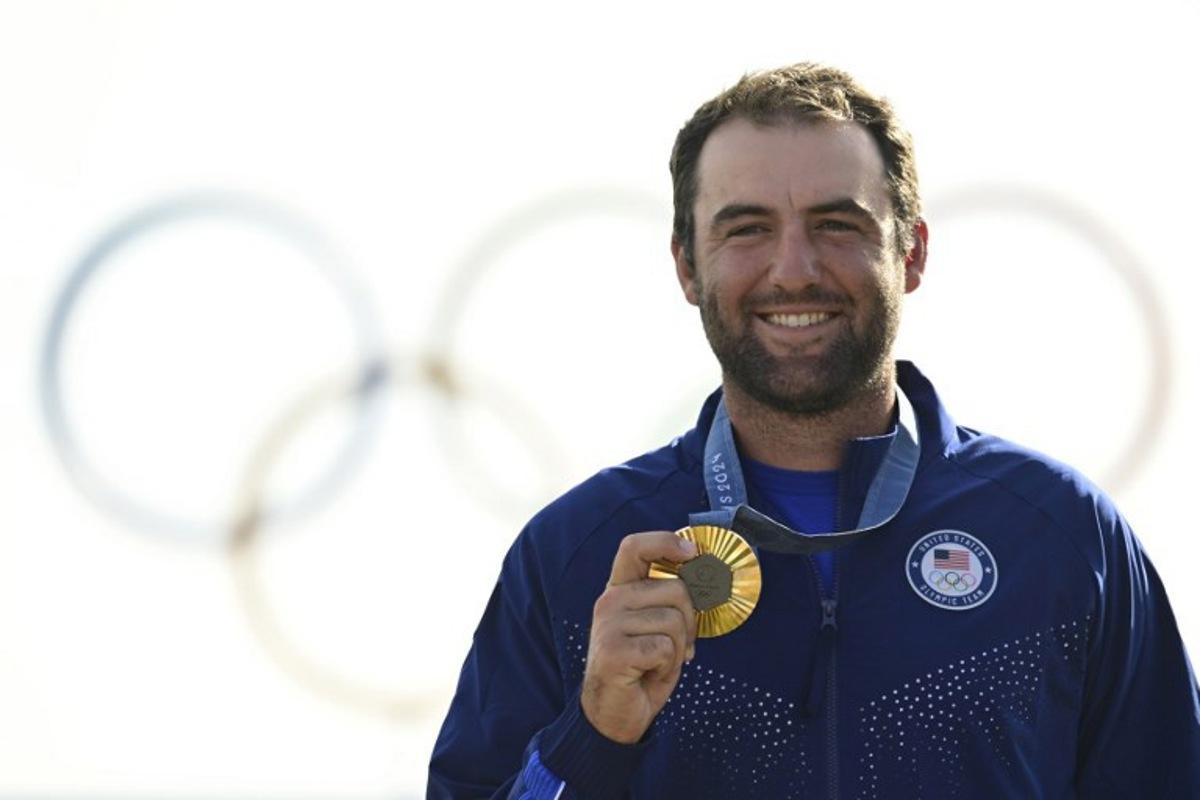 Gold medallist US' Scottie Scheffler poses for pictures on the podium after round 4 of the men's golf individual stroke play of the Paris 2024 Olympic Games at Le Golf National in Guyancourt, south-west of Paris on August 4, 2024. John MACDOUGALL / AFP
