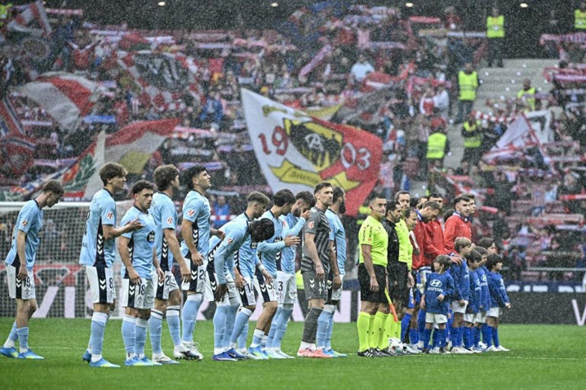 Teams line up under the rain before the start of the Spanish league football match between Club Atletico de Madrid and RC Celta de Vigo at the Metropolitano Stadium in Madrid on May 9, 2026. Javier SORIANO / AFP