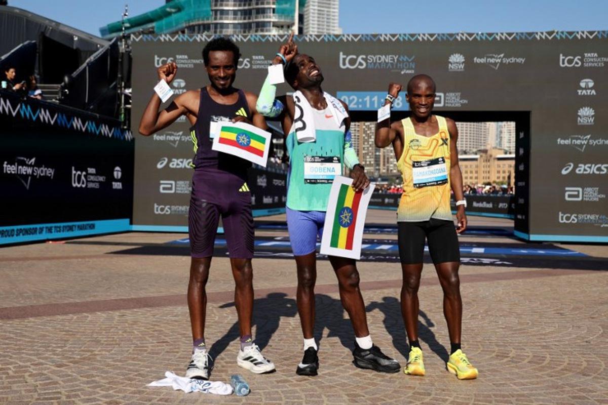 Winner Ethiopia's Addisu Gobena (C) reacts as he stands with second-placed Ethopia's Chimdessa Debele (L) and third-placed Lesotho's Tebello Ramakongoana after they crossed the finish line in the 2026 Sydney Marathon in Sydney on August 30, 2026. DAVID GRAY / AFP