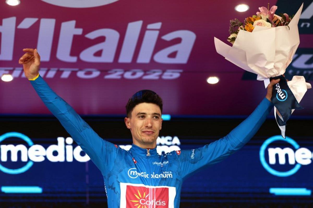 Cofidis' Belgian rider Sylvain Moniquet wears the best climber's blue jersey on the podium after the first stage of the 108th Giro d'Italia cycling race, 160km from Durres to Tirana in Albania, on May 9, 2025. Luca Bettini / AFP