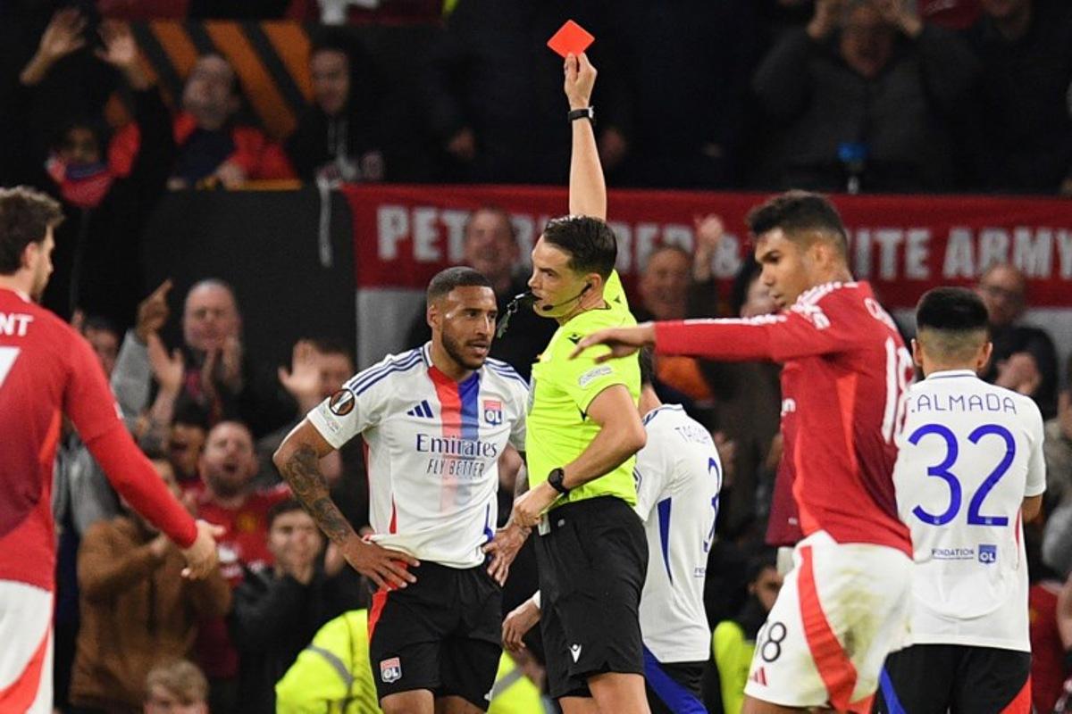 Swiss referee Sandro Scharer shows a red card to Lyon's French midfielder #08 Corentin Tolisso during the UEFA Europa league quarter-final final, second leg football match between Manchester United and Lyon at Old Trafford stadium in Manchester, north west England, on April 17, 2025. Oli SCARFF / AFP