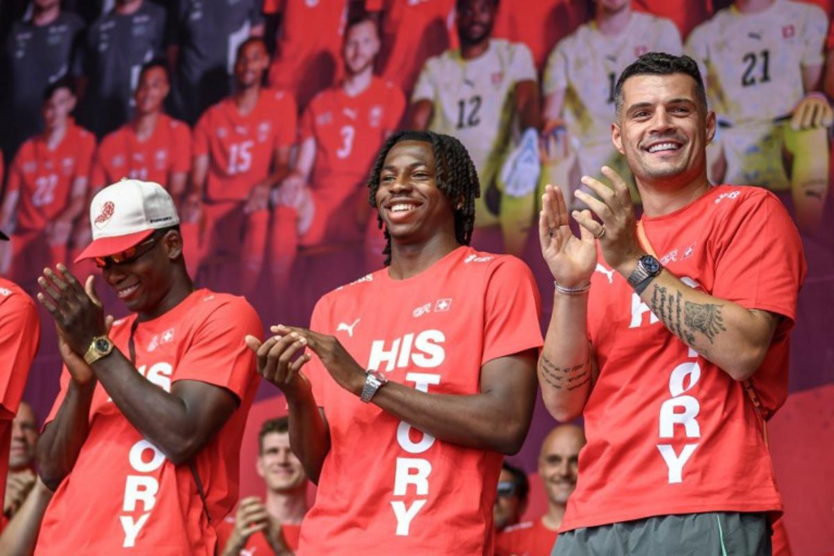 (From L) Switzerland's players forward #07 Breel Embolo, midfielder #09 Johan Manzambi and midfielder #10 Granit Xhaka applaud during a fan reception welcoming the team back to the country following its 2026 FIFA World Cup quarter-final match against Argentina, in Zurich on July 14, 2026. Fabrice COFFRINI / AFP