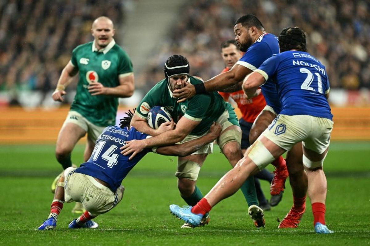 Ireland's number number eight Caelan Doris is tackled by France's wing Théo Attissogbe (#14) and France's lock Emmanuel Meafou (2nd R) during the Six Nations international rugby union match between France and Ireland at the Stade de France in Saint-Denis, Paris' suburb, on February 5, 2026. Julie SEBADELHA / AFP