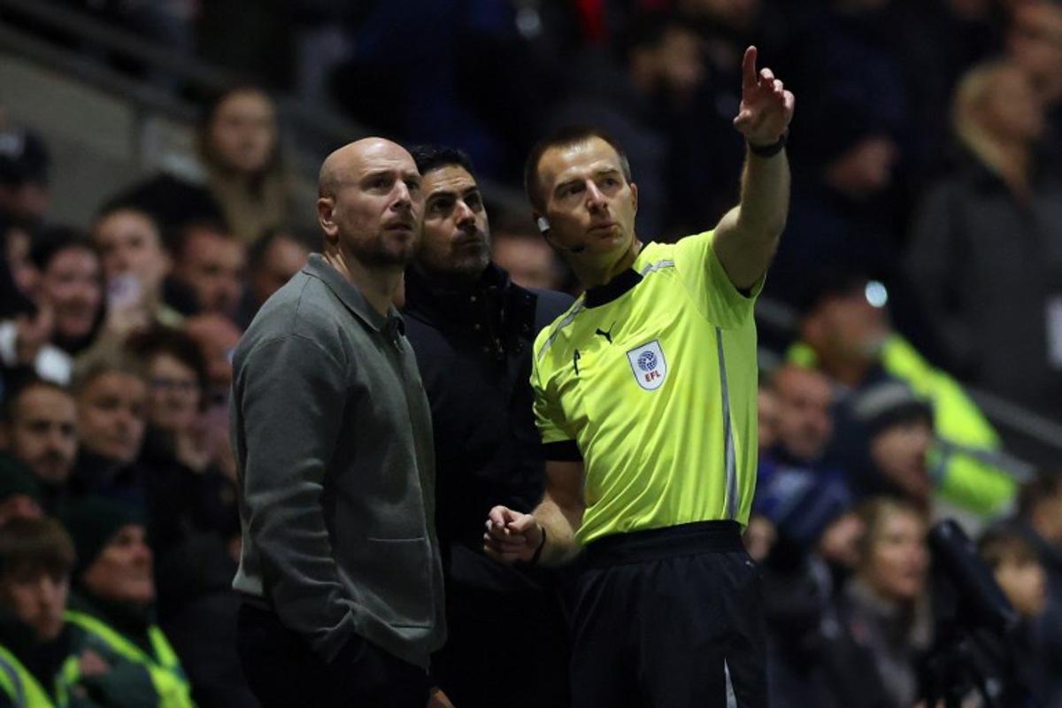 Referee Michael Salisbury (R) gestures towards a drone in the sky as he speaks to Arsenal's Spanish manager Mikel Arteta (C) and Fleetwood's English manager Matt Lawlor during the English League Cup fourth round football match between Fleetwood Town and Arsenal at Highbury Stadium in Fleetwood, north west England, on October 27, 2026. Darren Staples / AFP